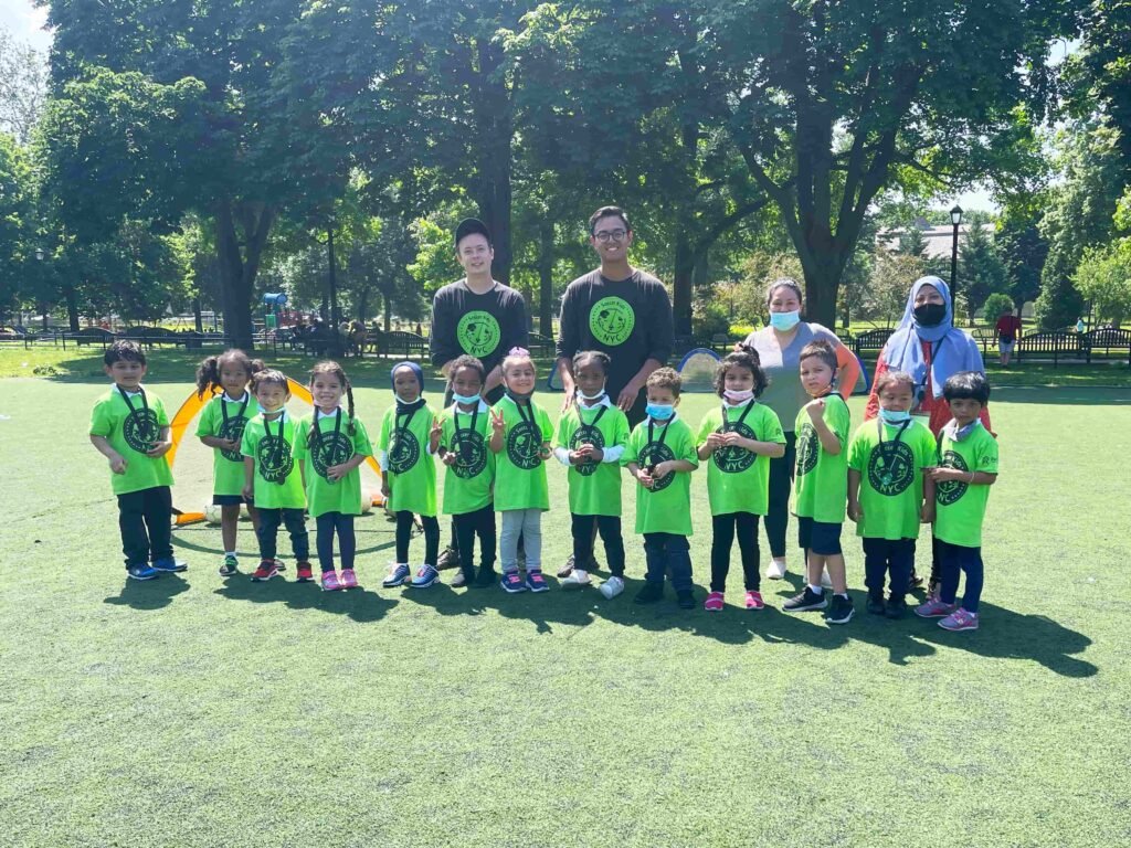 Toddlers from a local school are taking a group picture with their coaches from the instructional soccer program